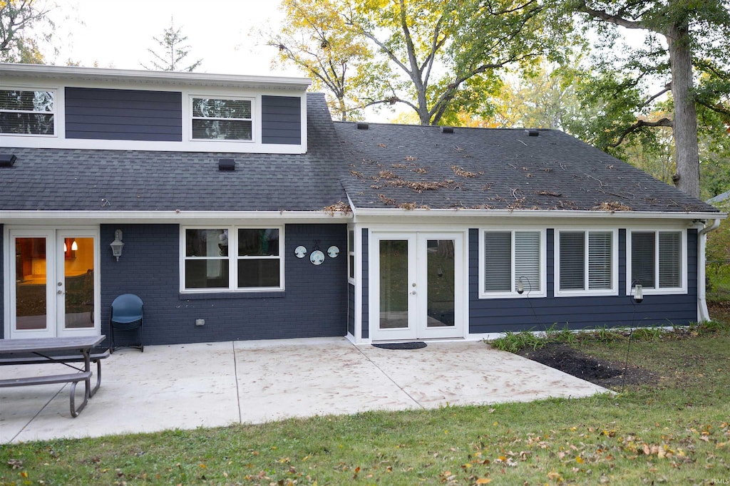 rear view of property with brick siding, french doors, a shingled roof, and a patio area