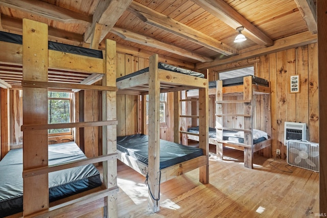 bedroom with light hardwood / wood-style floors, wood walls, wooden ceiling, and beam ceiling