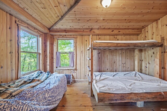 bedroom with light hardwood / wood-style floors, wood ceiling, wood walls, and lofted ceiling