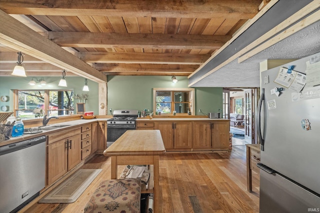 kitchen featuring beamed ceiling, light hardwood / wood-style flooring, sink, pendant lighting, and appliances with stainless steel finishes