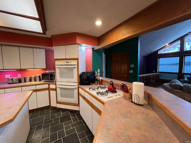 kitchen with white appliances, white cabinetry, and lofted ceiling