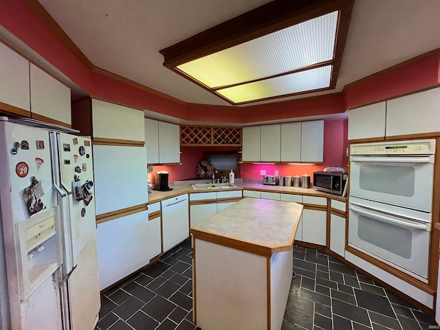 kitchen featuring a kitchen island, sink, white cabinetry, and white appliances