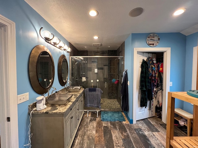 bathroom with vanity, a textured ceiling, walk in shower, and wood-type flooring