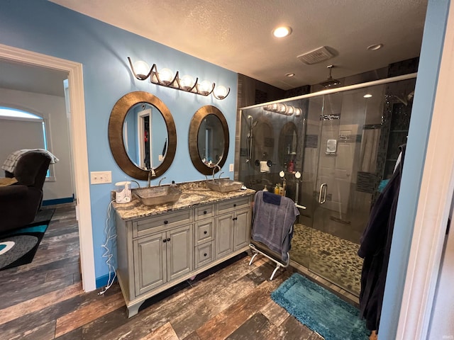 bathroom featuring vanity, a textured ceiling, a shower with shower door, and hardwood / wood-style flooring