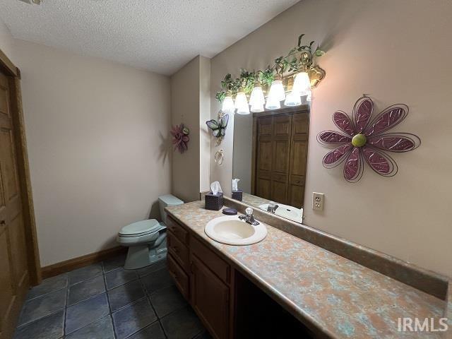 720 Ln 800 Snow Lk, Fremont, IN 46737 - bathroom featuring a textured ceiling, toilet, vanity, tile patterned floors, and baseboards