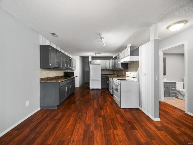 kitchen featuring white appliances, tasteful backsplash, a textured ceiling, gray cabinets, and dark hardwood / wood-style floors