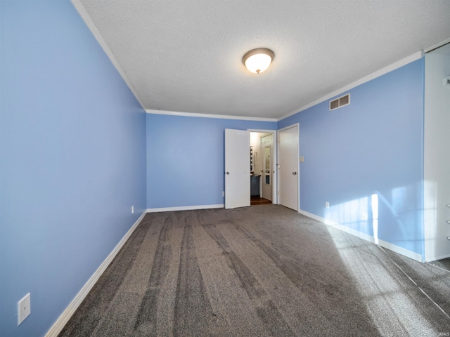 spare room with ornamental molding, a textured ceiling, and dark colored carpet