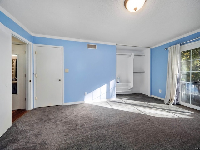 unfurnished bedroom with ornamental molding, access to exterior, a textured ceiling, and dark colored carpet