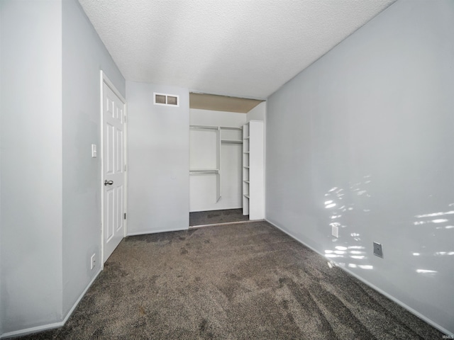 unfurnished bedroom featuring a closet, a textured ceiling, and dark colored carpet