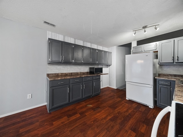 kitchen with dark wood-type flooring, backsplash, a textured ceiling, and white refrigerator