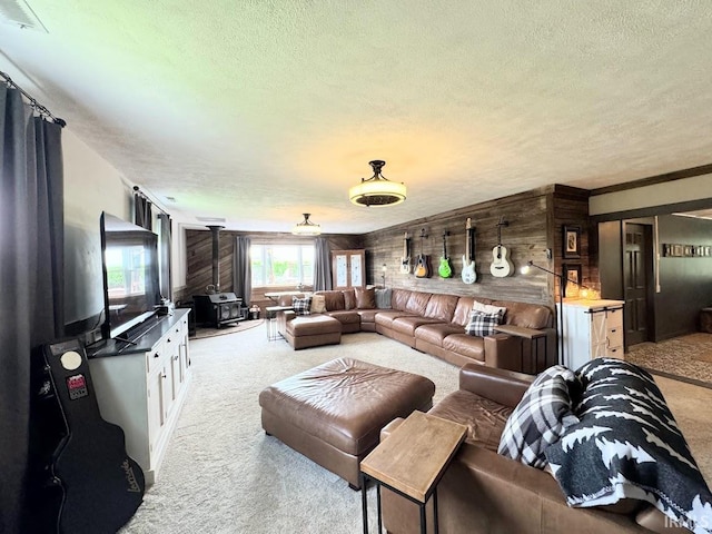 carpeted living room with a wood stove, a textured ceiling, and wood walls