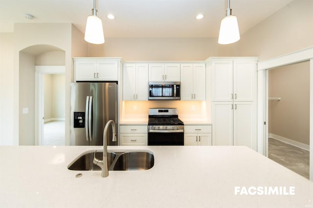 kitchen featuring appliances with stainless steel finishes, white cabinetry, sink, and hanging light fixtures