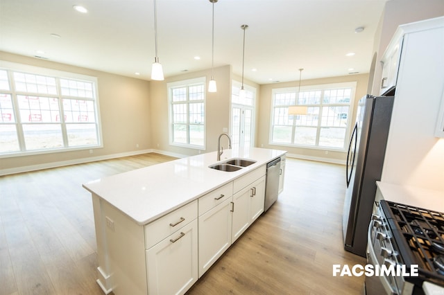 kitchen with white cabinets, decorative light fixtures, and a center island with sink