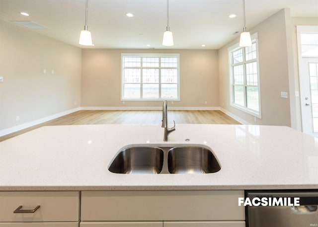 kitchen with sink, light stone countertops, a wealth of natural light, and stainless steel dishwasher