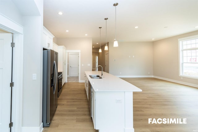 kitchen with stainless steel refrigerator with ice dispenser, a center island with sink, sink, white cabinets, and light hardwood / wood-style floors