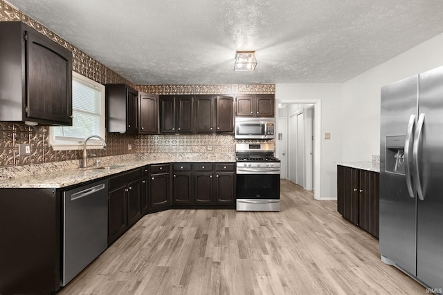 kitchen with appliances with stainless steel finishes, light hardwood / wood-style flooring, sink, and dark brown cabinets