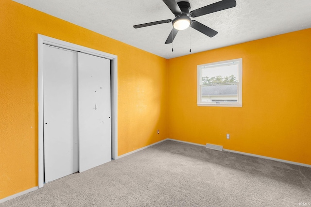 unfurnished bedroom with a closet, ceiling fan, a textured ceiling, and carpet floors