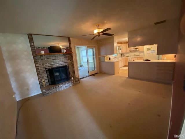 unfurnished living room featuring light carpet, a brick fireplace, and ceiling fan