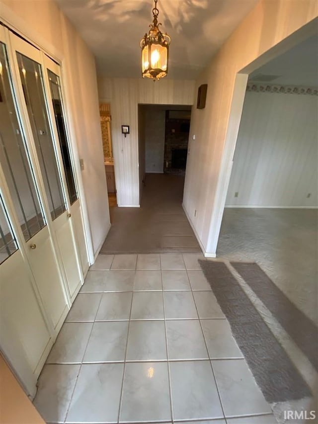 corridor with a chandelier and light tile patterned flooring