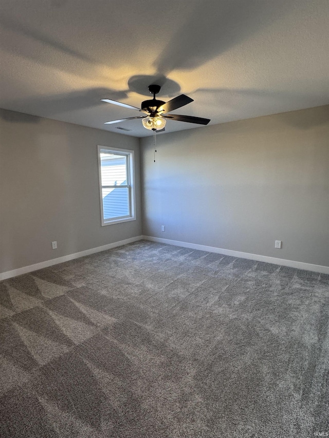 empty room with a ceiling fan, dark colored carpet, and a textured ceiling