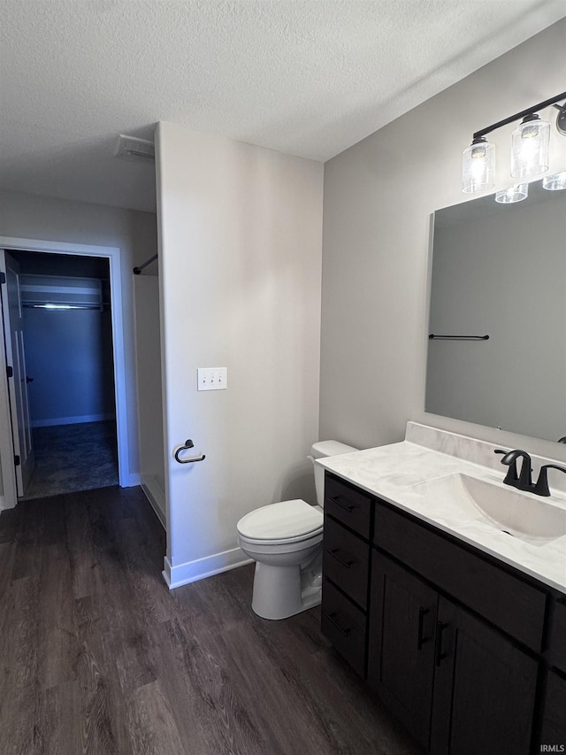 bathroom with a textured ceiling, vanity, toilet, and wood finished floors