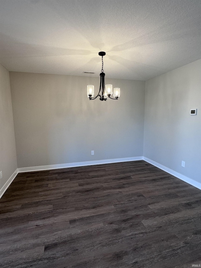 unfurnished room with an inviting chandelier, baseboards, dark wood-style floors, and visible vents