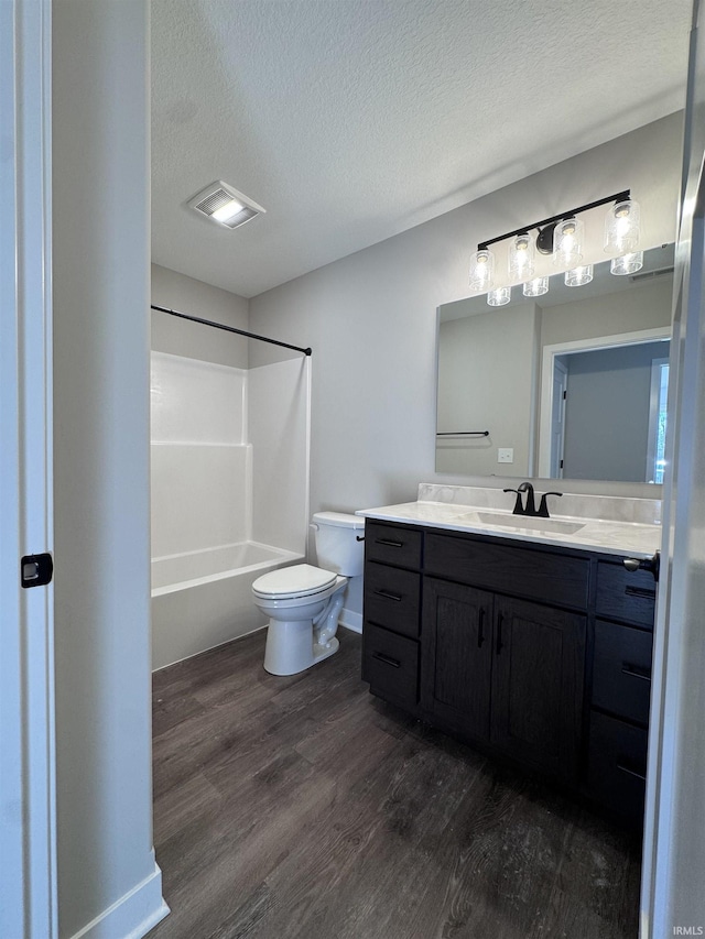 bathroom featuring a textured ceiling, visible vents, wood finished floors, vanity, and toilet
