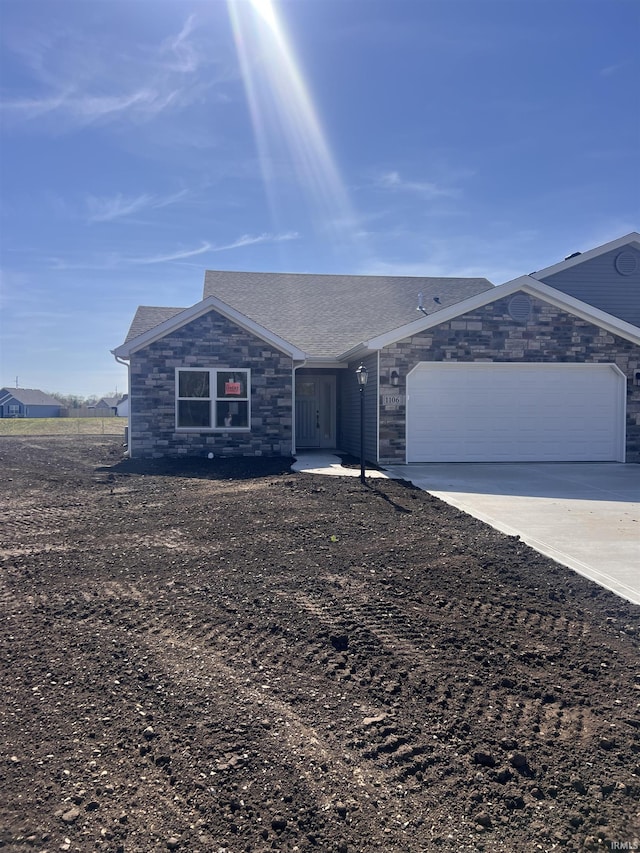 ranch-style house featuring an attached garage, concrete driveway, and stone siding