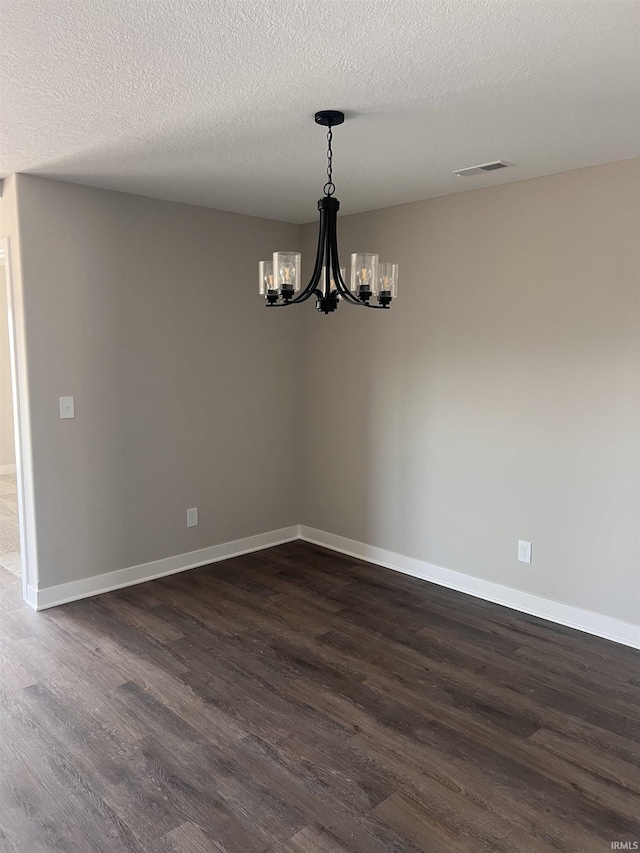 empty room featuring baseboards, visible vents, dark wood-style floors, and a chandelier