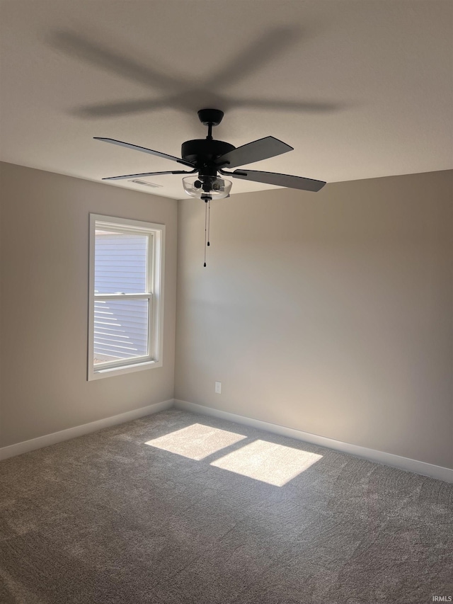 empty room with carpet floors, a ceiling fan, and baseboards