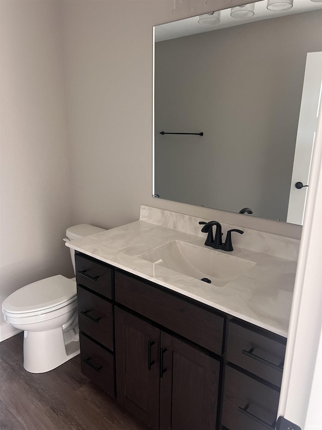 bathroom with toilet, wood finished floors, and vanity