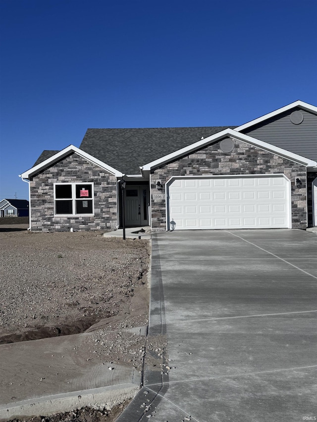 ranch-style house with concrete driveway, a shingled roof, stone siding, and a garage