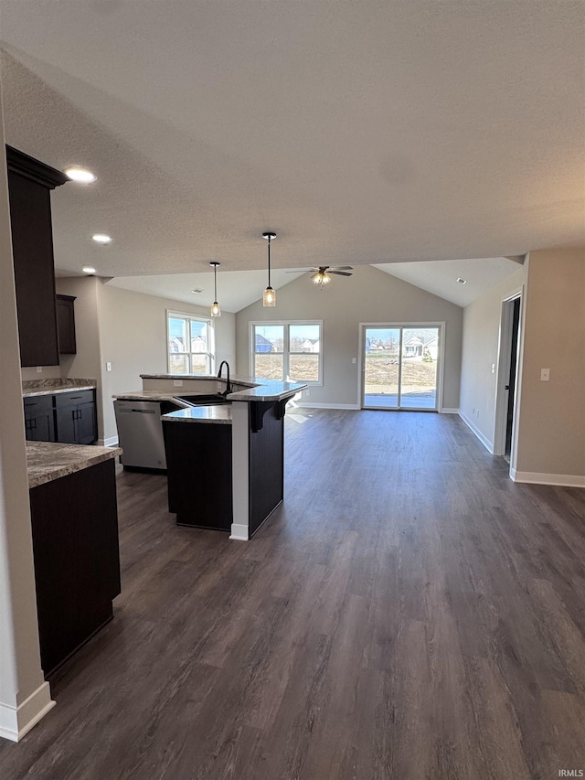 kitchen featuring baseboards, open floor plan, plenty of natural light, and a sink