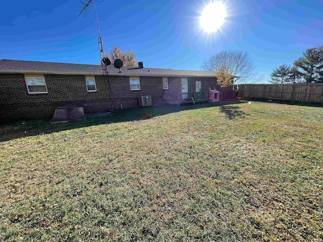 rear view of property featuring a lawn and central AC