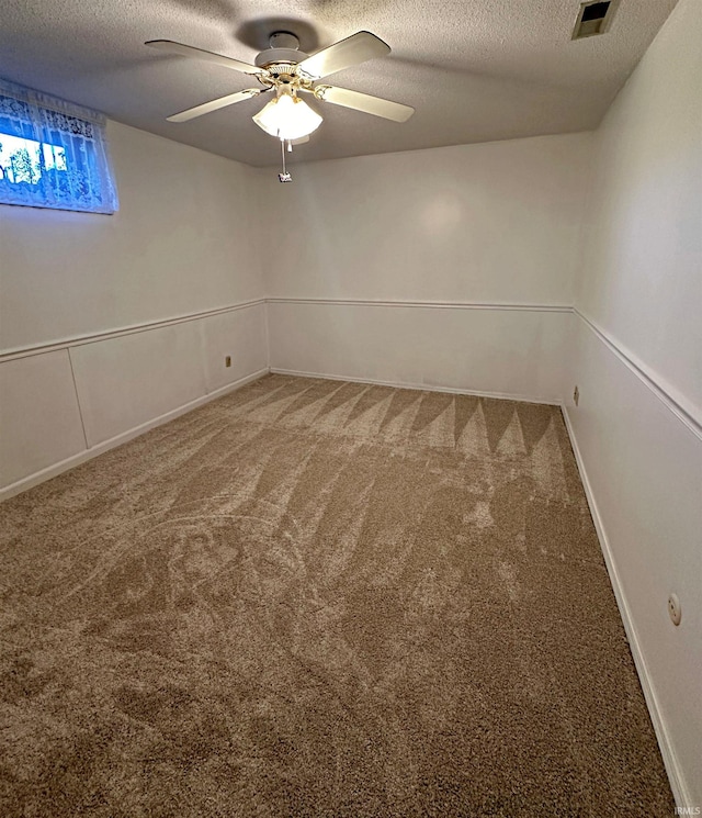 carpeted spare room featuring ceiling fan and a textured ceiling