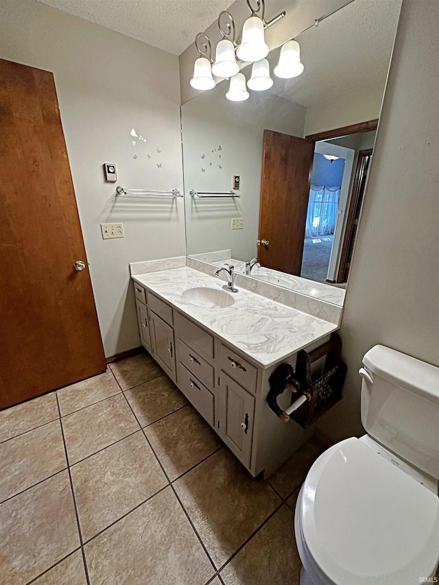 bathroom with vanity, toilet, a textured ceiling, and tile patterned flooring