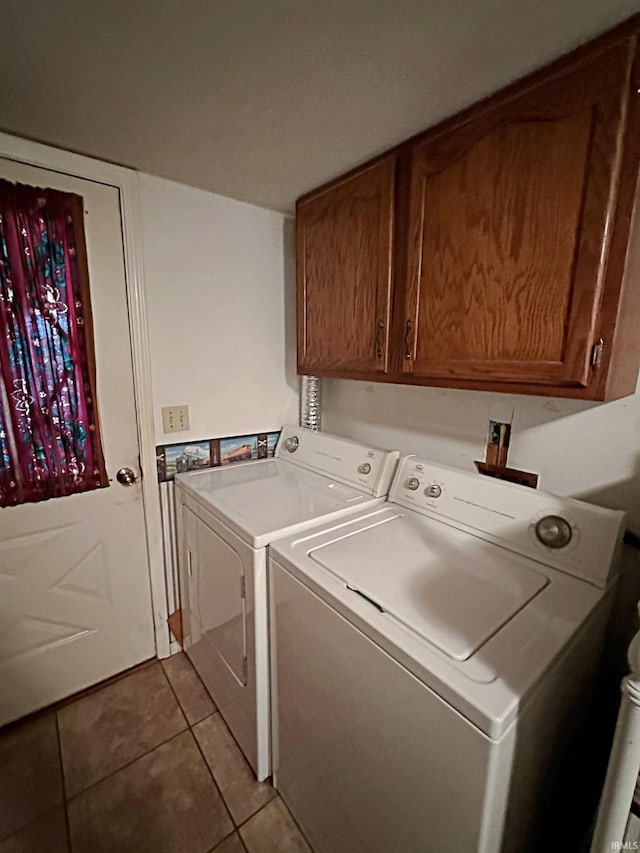 laundry area featuring washer and clothes dryer, light tile patterned floors, and cabinets