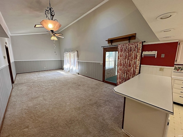 unfurnished living room with crown molding, light colored carpet, high vaulted ceiling, and ceiling fan