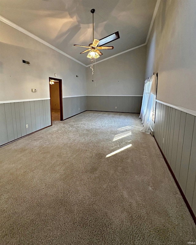 carpeted spare room featuring ornamental molding, vaulted ceiling, and ceiling fan