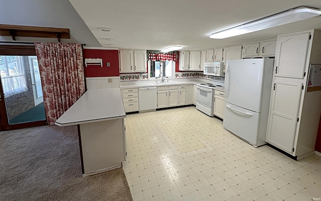 kitchen with kitchen peninsula, white cabinetry, sink, and white appliances