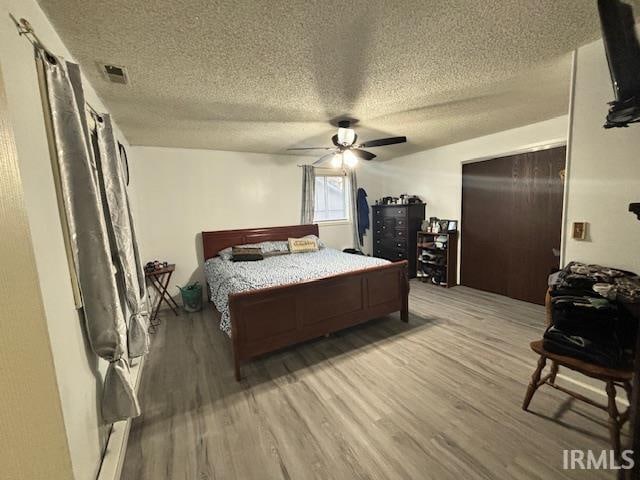 bedroom featuring a textured ceiling, wood-type flooring, and ceiling fan