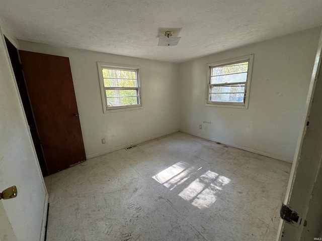 unfurnished bedroom with a textured ceiling and multiple windows