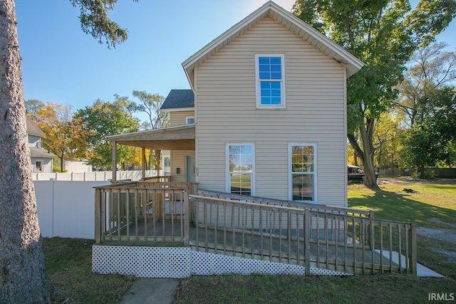 back of property featuring a wooden deck and a lawn