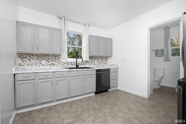 kitchen featuring gray cabinets, black dishwasher, sink, and tasteful backsplash