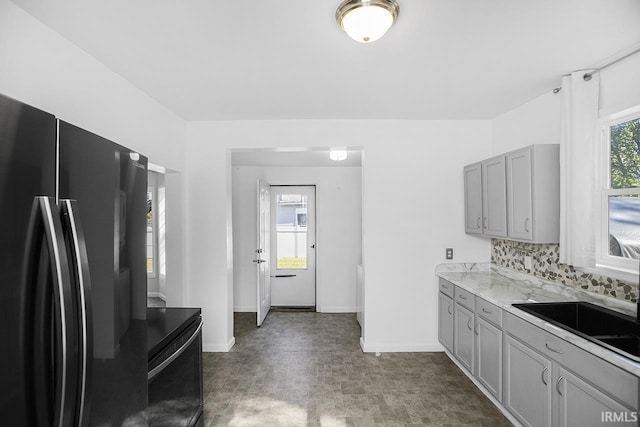 kitchen featuring a healthy amount of sunlight, black refrigerator, backsplash, and gray cabinetry