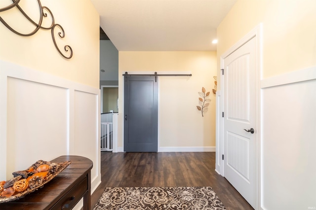 corridor with a barn door and dark hardwood / wood-style floors