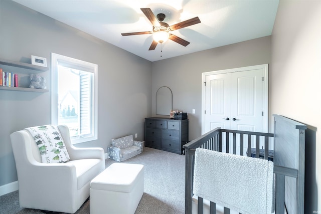 bedroom featuring a nursery area, carpet floors, a closet, and ceiling fan