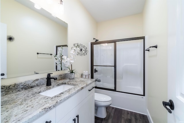 full bathroom featuring vanity, hardwood / wood-style floors, toilet, and shower / bath combination with glass door