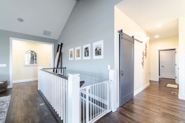 hallway featuring lofted ceiling, dark hardwood / wood-style flooring, and a barn door