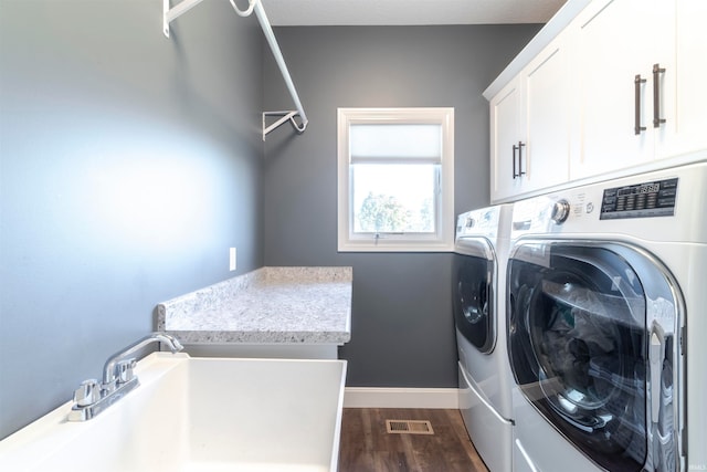 washroom with sink, washer and clothes dryer, dark wood-type flooring, and cabinets